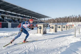 Biathlète skiant devant le pas de tir d'un stade enneigé